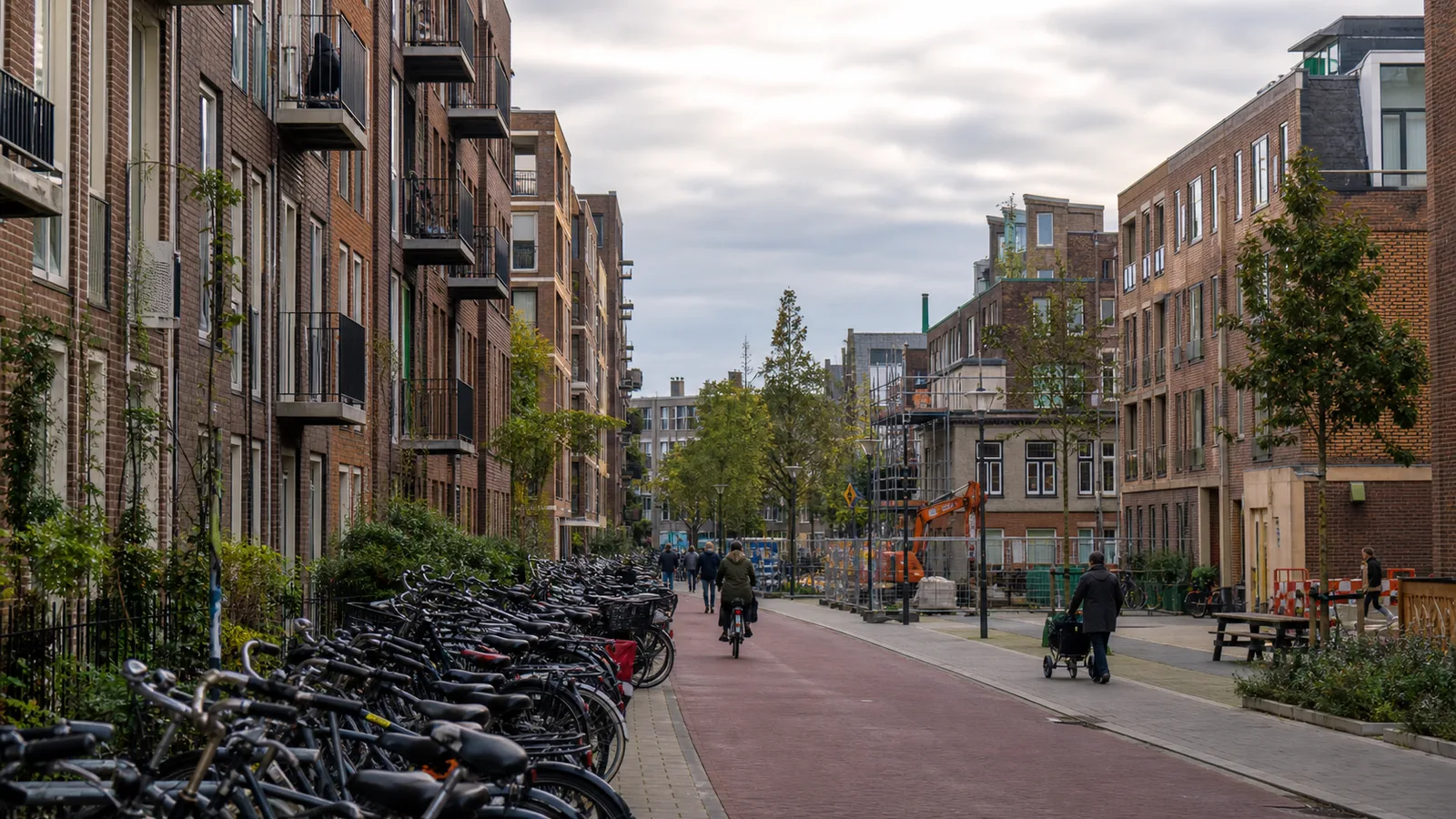 A compact Utrecht residential street with apartment buildings, parked bicycles, pedestrians and construction work sharing limited public space.